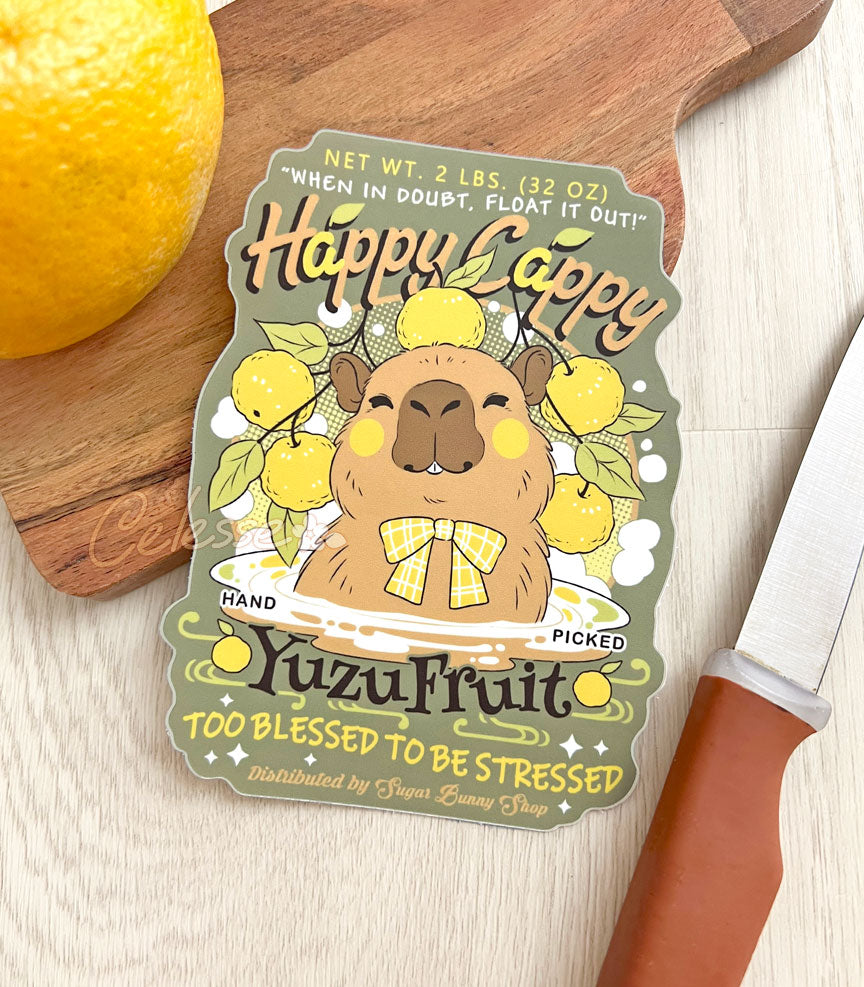 A vinyl sticker of a vintage-style logo for Happy Cappy Yuzu Fruit, the illustration featuring a blissful-looking capybara sitting in a hot spring pool with yuzu spread around it. The secondary text reads "When in doubt, float it out!" and "Too blessed to be stressed."