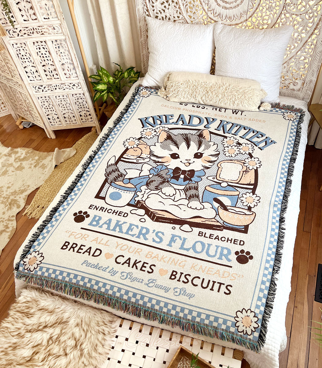 A photo of a woven blanket featuring a vintage-style logo for Kneady Kitten Baker&