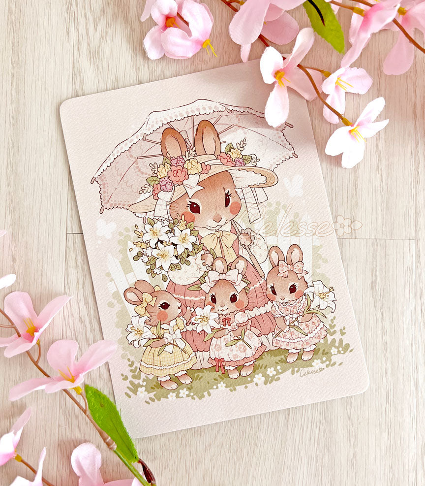 A photo of an art print featuring a mother rabbit and her three daughters dressed in their Sunday best and holding lilies.