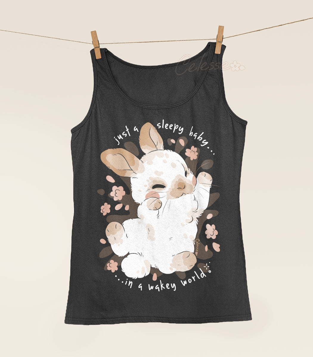 Dark gray tank top with a cartoon bunny design hanging from a clothesline. The text reads "Just a sleepy baby in a wakey world."