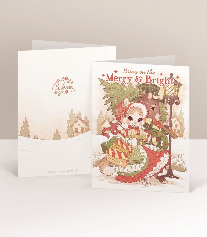 A Christmas card featuring a cat couple in vintage clothing carrying shopping bags and a Christmas tree through a snowy village. The text reads "Bring on the Merry & Bright."