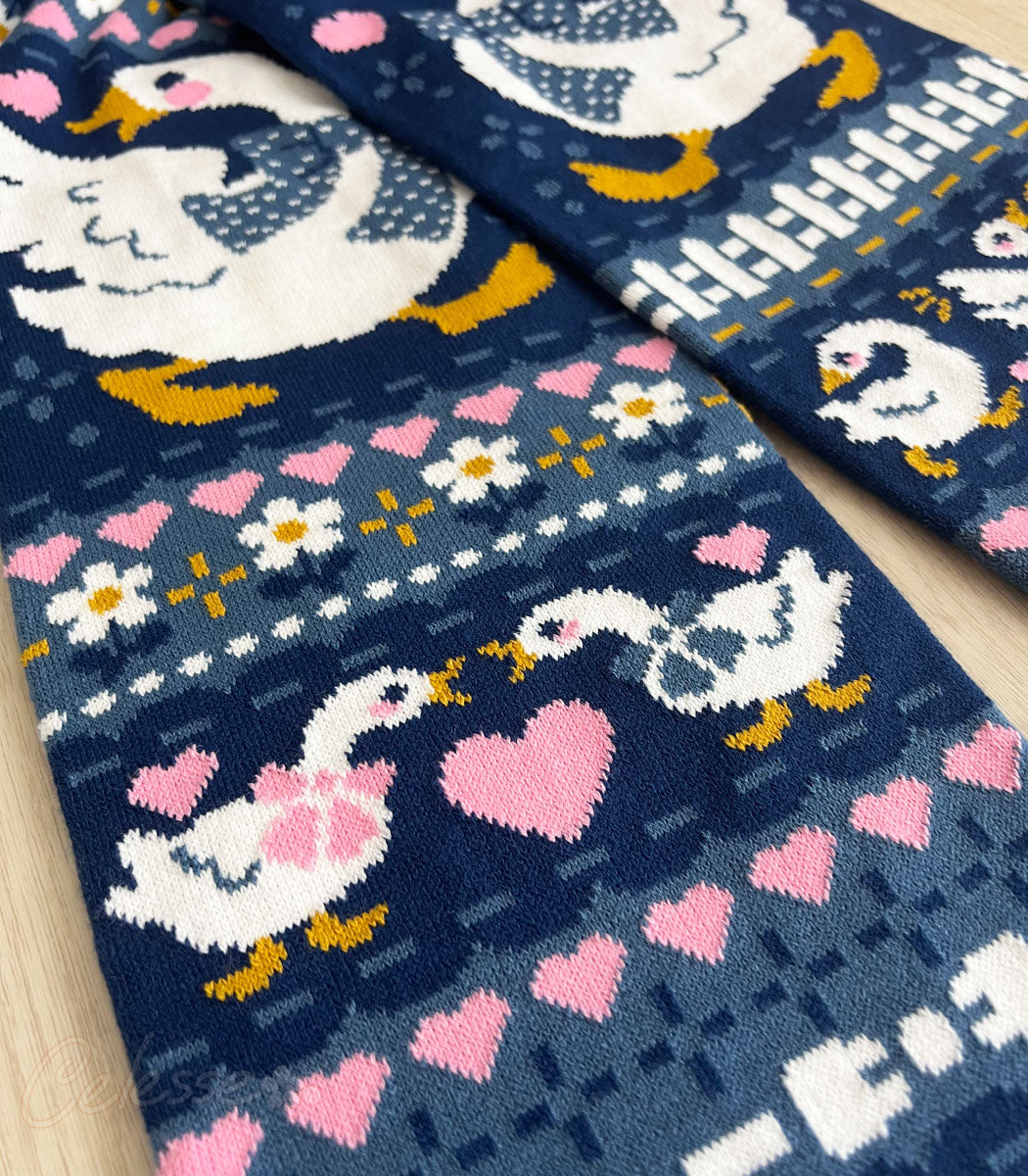 A close-up photo of a blue knit scarf with a vintage-style goose design.