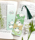 A photo of a bookmark placed atop an open book, the artwork featuring a group of fat, blob-shaped frogs gathered together on a log.