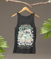 Blobfrogs Frog Froth Bath Soap Tank Top. Dark gray tank top with frog-themed graphic design on a hanger against a brown background with green leaves.