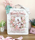 A white canvas tote bag with a whimsical vintage-style logo for Blossom Opossum Toilet Water, styled on a wooden surface with decorative flowers, a pink purse, and a floral scarf.