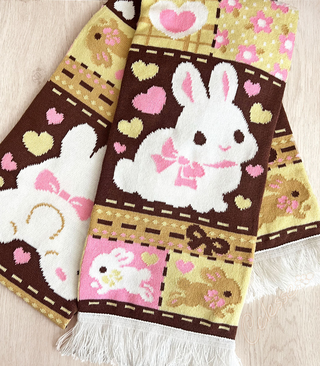 Knit scarf with a patchwork bunny rabbit design on a light wooden surface.