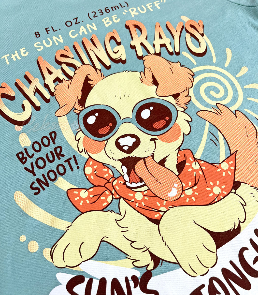 A close-up photo of the print of a dusty blue shirt with a vintage-style logo featuring a floppy-eared dog wearing sunglasses and a bandana, with their tongue hanging out.