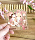 A photo of a handing holding a clear vinyl sticker with country cows in a barn   above a wooden surface with flowers and a small fence in the background.