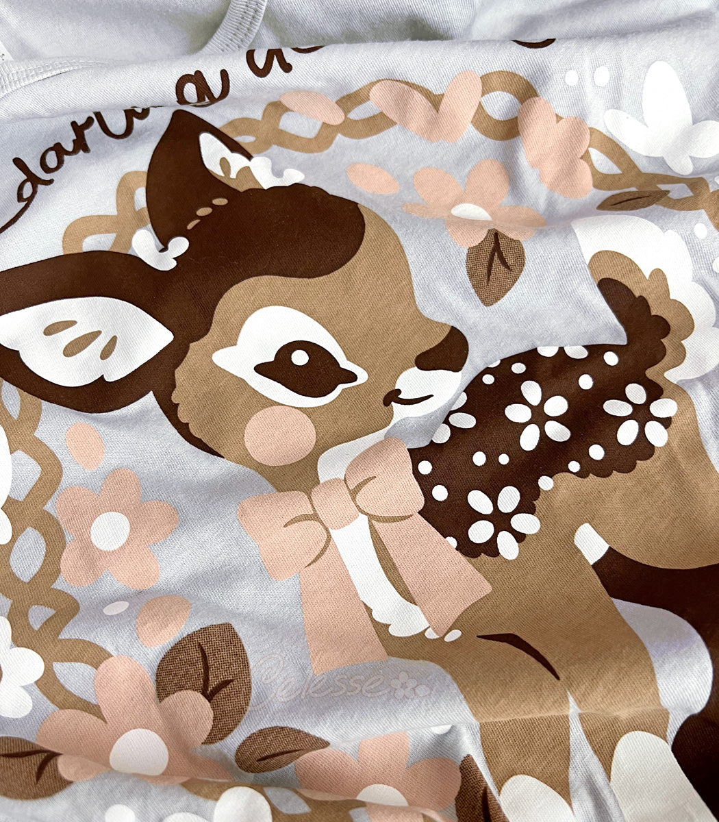 Close-up of a shirt print with deer and floral patterns on a silver background.