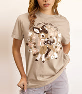 A woman wearing a tan-colored shirt featuring a print of a baby deer with flower spots. The text reads "darling deer".
