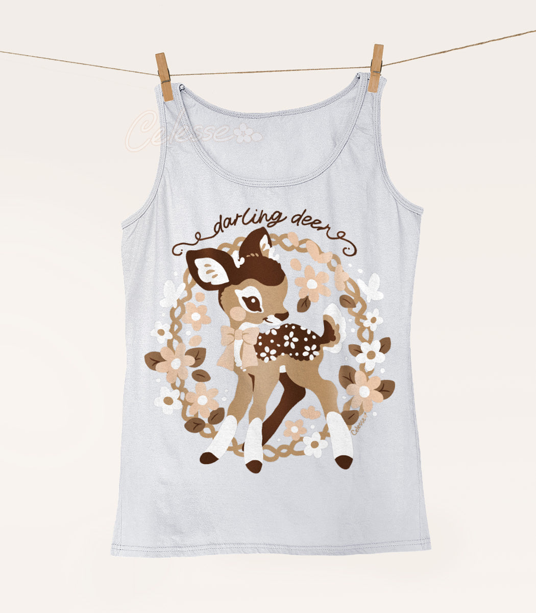 A silver colored tank top hanging from a string with clothespins, the print featuring a baby deer in a wreath of flowers with the words "darling deer."