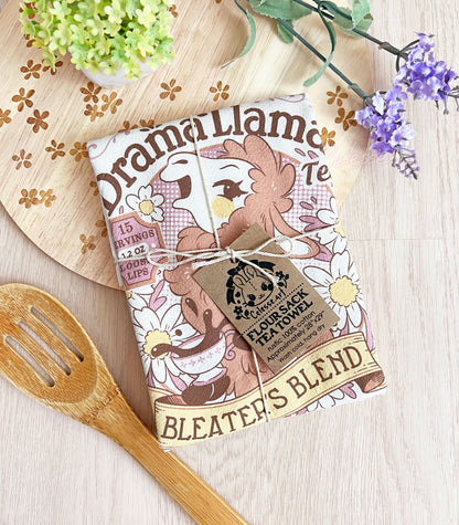 A folded white kitchen tea towel tied with twine with a vintage-style logo for Drama Llama Bleater&