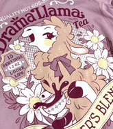 A close up photo of a muted lilac shirt with a print for a faux vintage-style logo for Drama Llama Tea, the art featuring a gossipy llama spilling the tea.