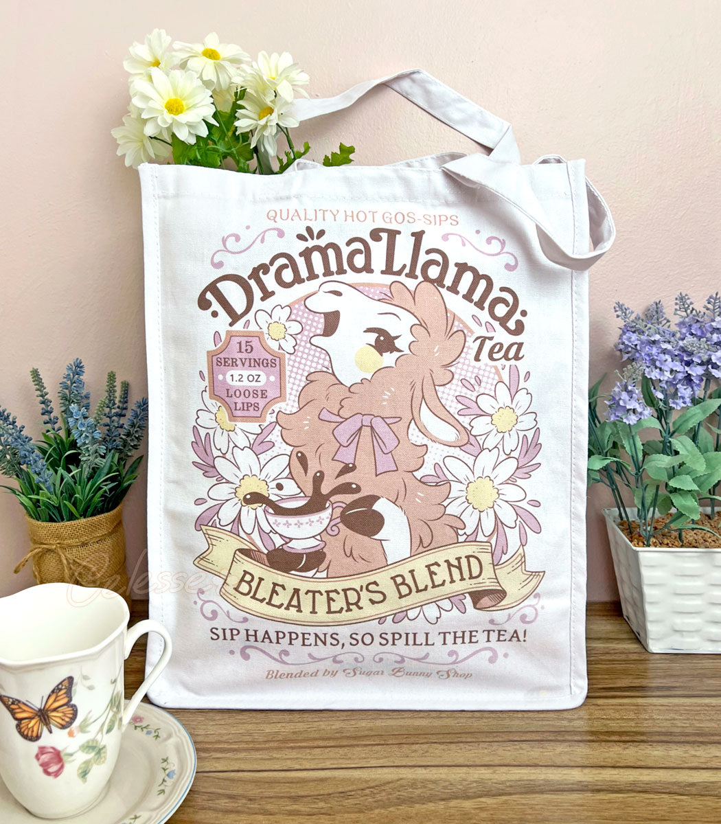 A white canvas tote bag with a gossipy llama surrounded by flowers in a vintage-style logo for "Drama Llama Bleater&