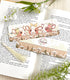 A photo of a bookmark placed atop an open book, the artwork featuring three country cows peeking over the top of a fence.