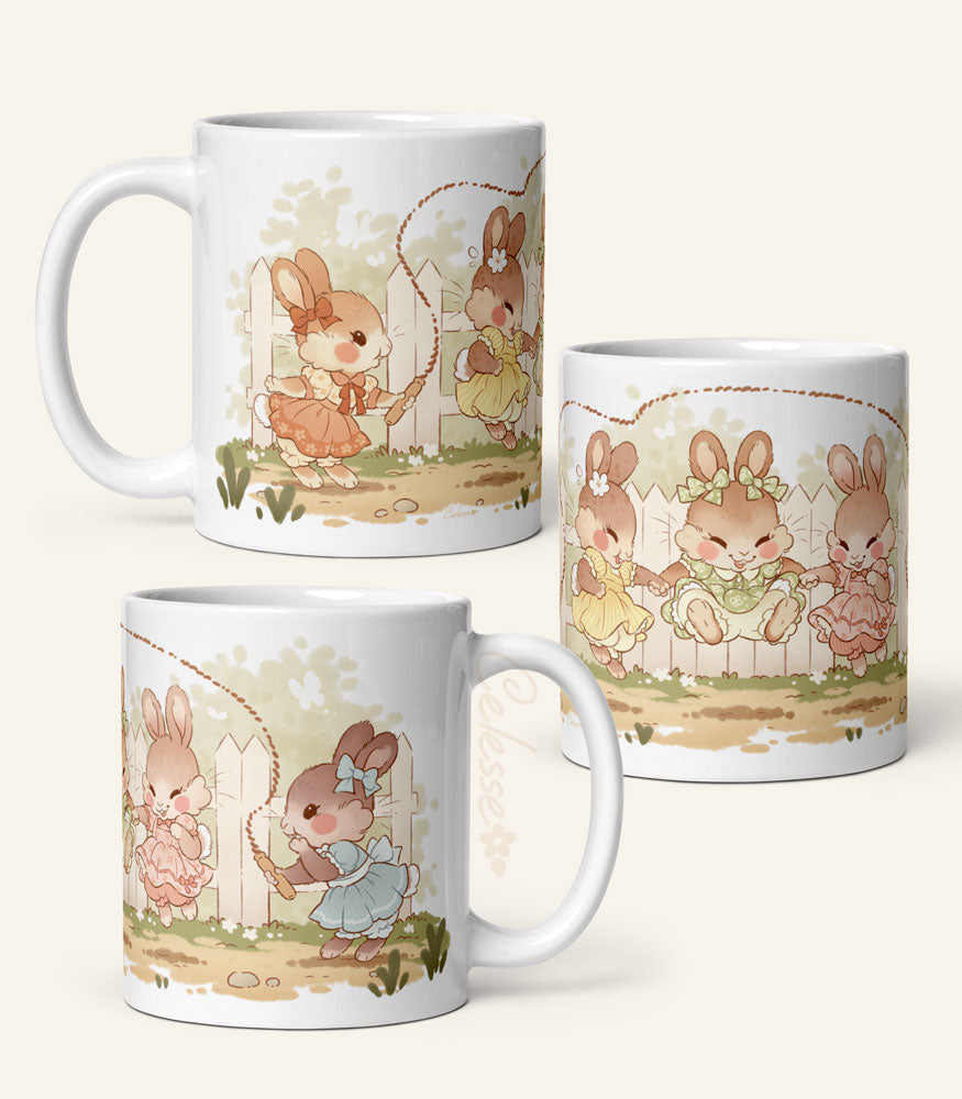 Photos of each side of an 11 oz. ceramic mug with a print featuring art of a bunch of bunny girls playing jump rope in vintage dresses.