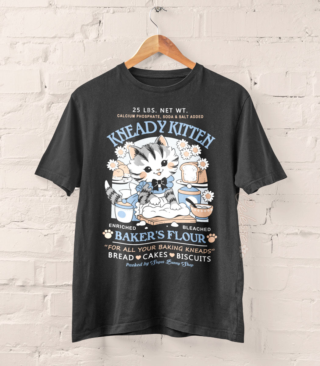 A photo of a dark gray shirt on a wood hanger, the print featuring a faux logo for Kneady Kitten Baker&
