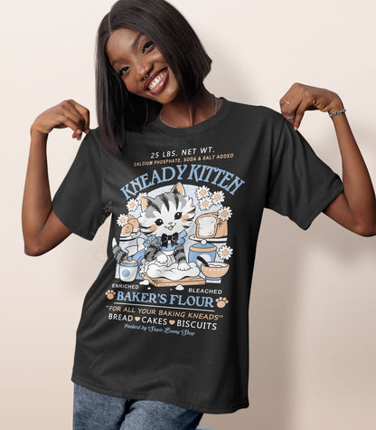 A woman wearing a dark gray shirt with a print of a faux vintage-style logo for Kneady Kitten Baker&