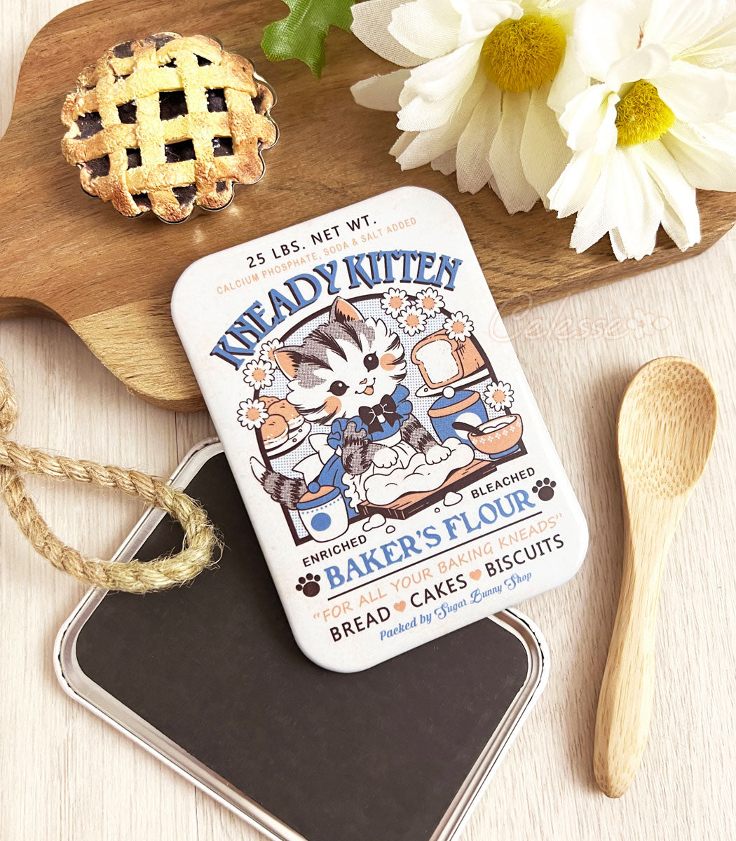 A photo of a rrectangular refrigerator magnet featuring artwork of a vintage-style logo for Kneady Kitten Baker&