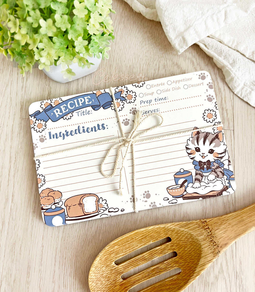 Cute recipe card with cartoon cat design on a wooden surface with a wooden spoon and plant.