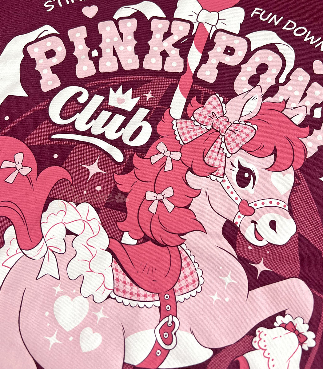 A close-up photo of the print of a maroon shirt with a vintage-style logo featuring a prancing pink pony and the title "Pink Pony Club."