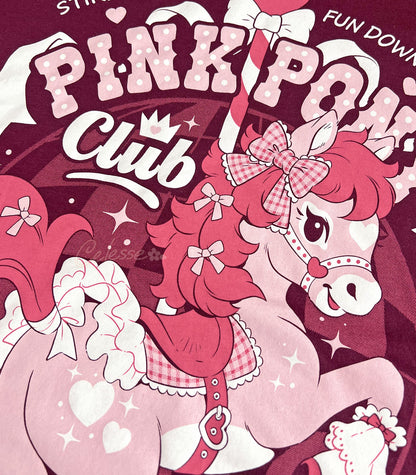 A close-up photo of the print of a maroon shirt with a vintage-style logo featuring a prancing pink pony and the title "Pink Pony Club."