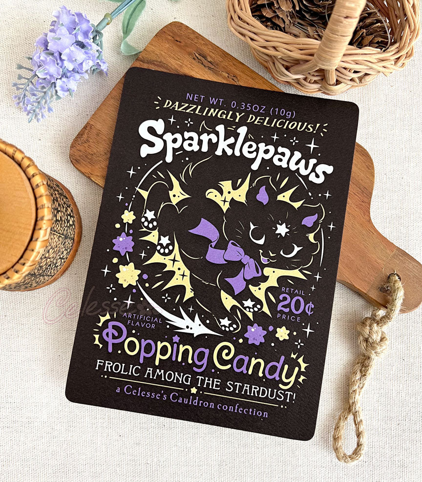 An art print of a retro faux candy logo for Sparklepaws Popping Candy, the art featuring a black cat with star paw pads leaping among bursting sparkles. The flavor text reads, "Dazzlingly delicious!" and "Frolic among the stardust!"