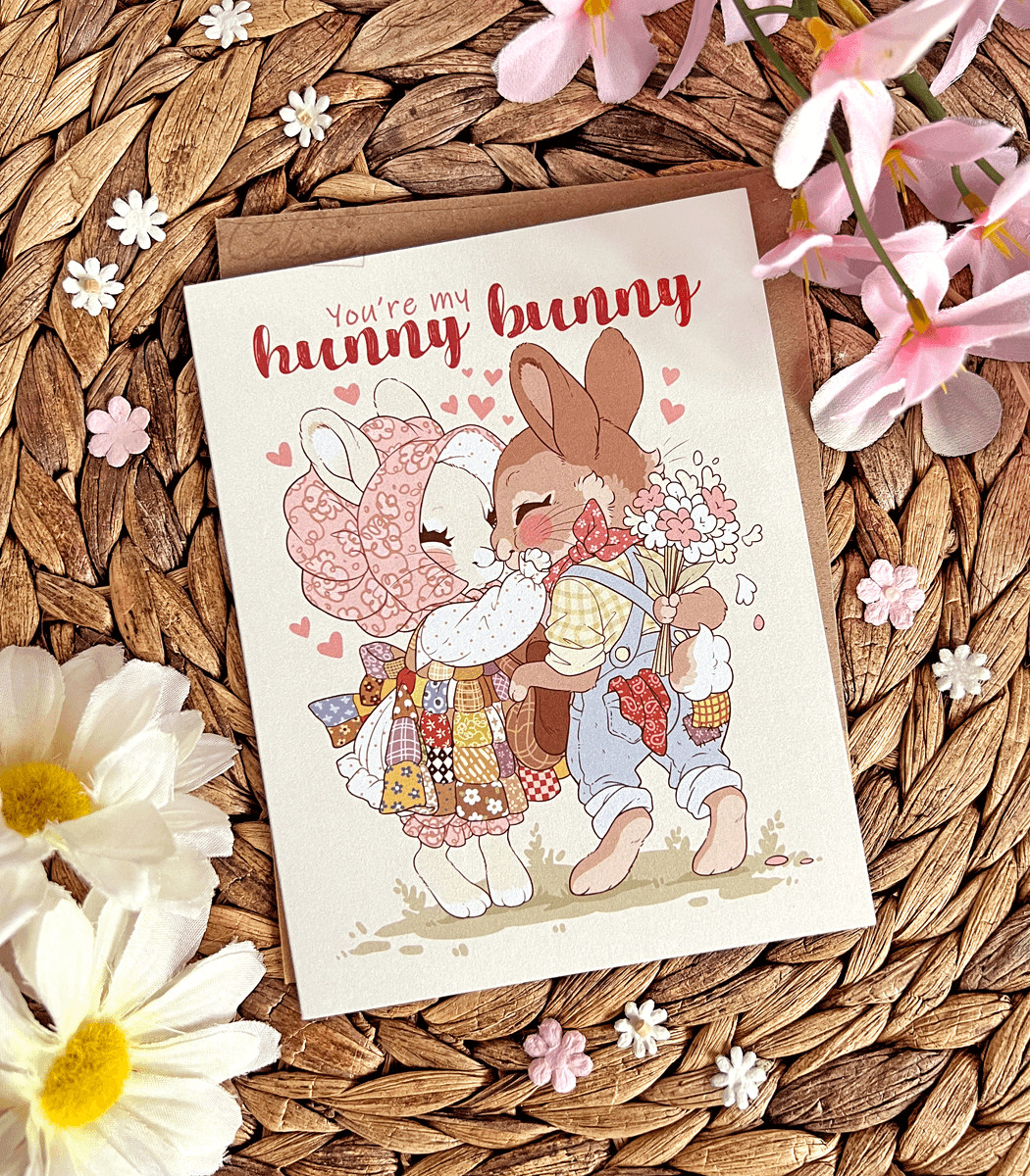 A photo of a vintage-style greeting card featuring soft artwork of two bunnies kissing. The text reads "You're my hunny bunny"